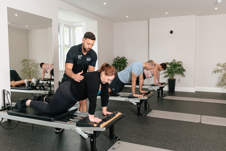 Trainer helps during Pilates class at Hatt Clinic