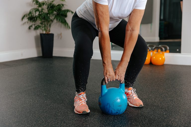 Person lifting blue kettlebell weight