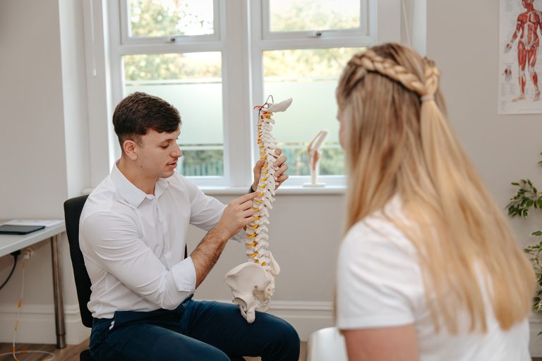 Physiotherapist pointing on skeleton of the spine