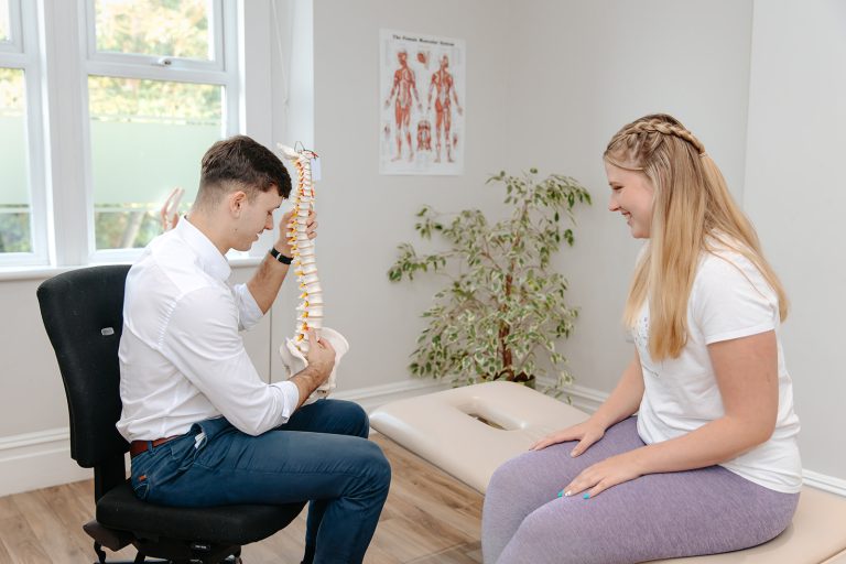 Physiotherapist showing skeleton spine to patient