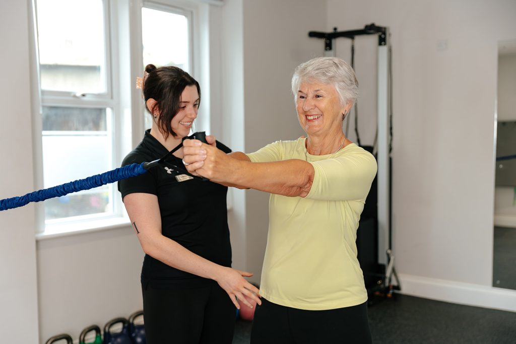 Woman using stretch band in Rehab Class at Hatt Clinic