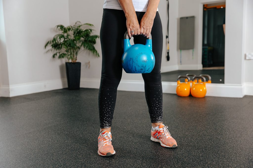 Woman lifting kettlebell weight during Strength and Movement class