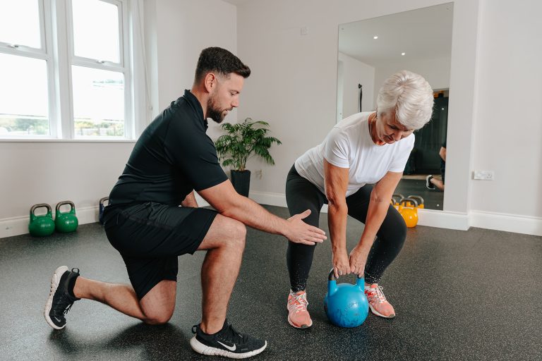 Woman lifting kettlebell weight during Strength and Movement class