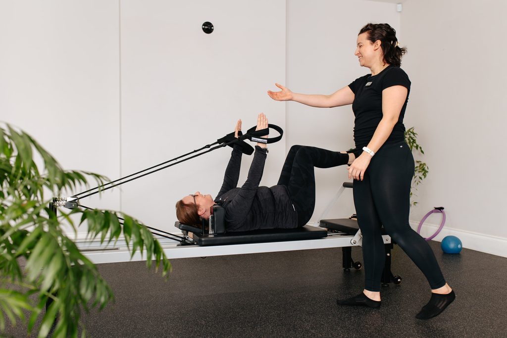 Pilates Instructor reaching Pilates using a Reformer machine